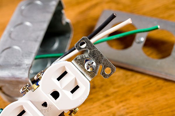 Now Electric | electrical outlet with various parts on wooden table